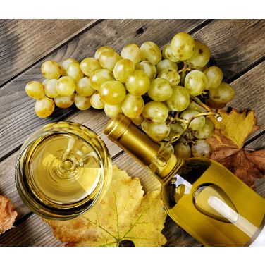 Wine grapes and a bottle with glass on a table