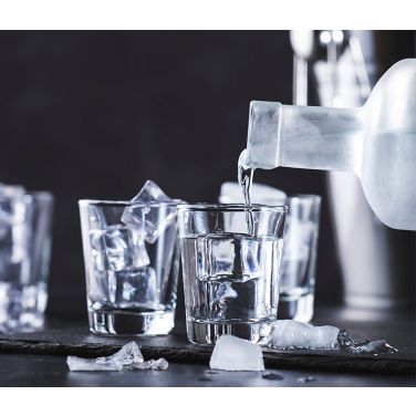 Vodka bottle being poured in shot glasses