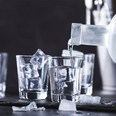 Vodka bottle being poured in shot glasses
