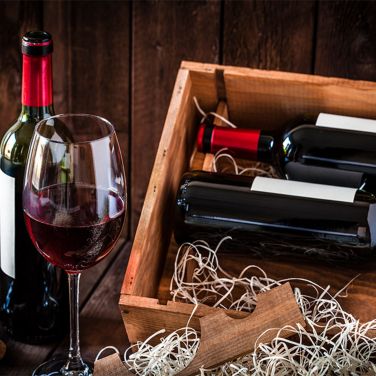 Bottles of red wine with a glass in a wooden case